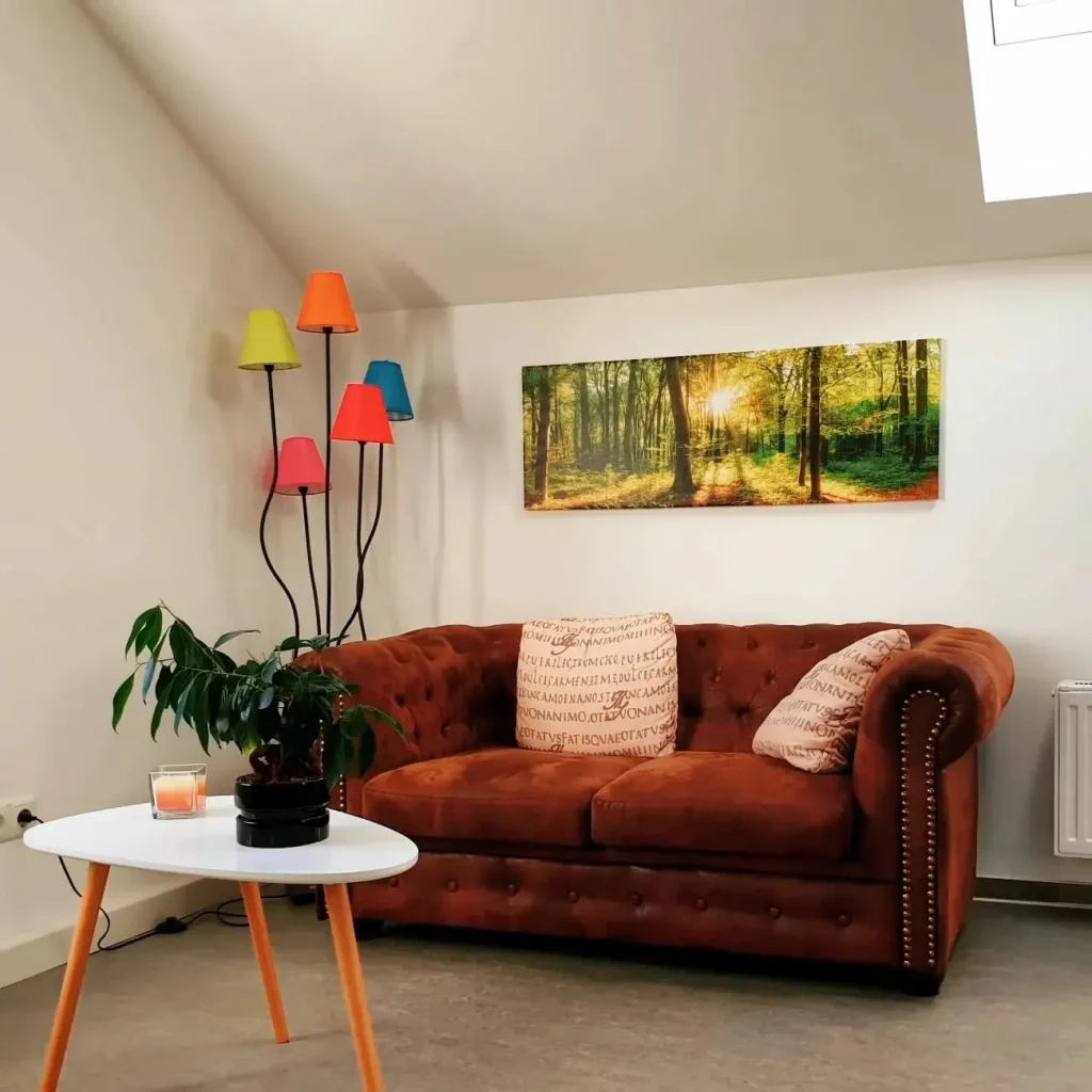 Ein Therapiezimmer mit einer bunten Stehlampe und einem roten Sofa.