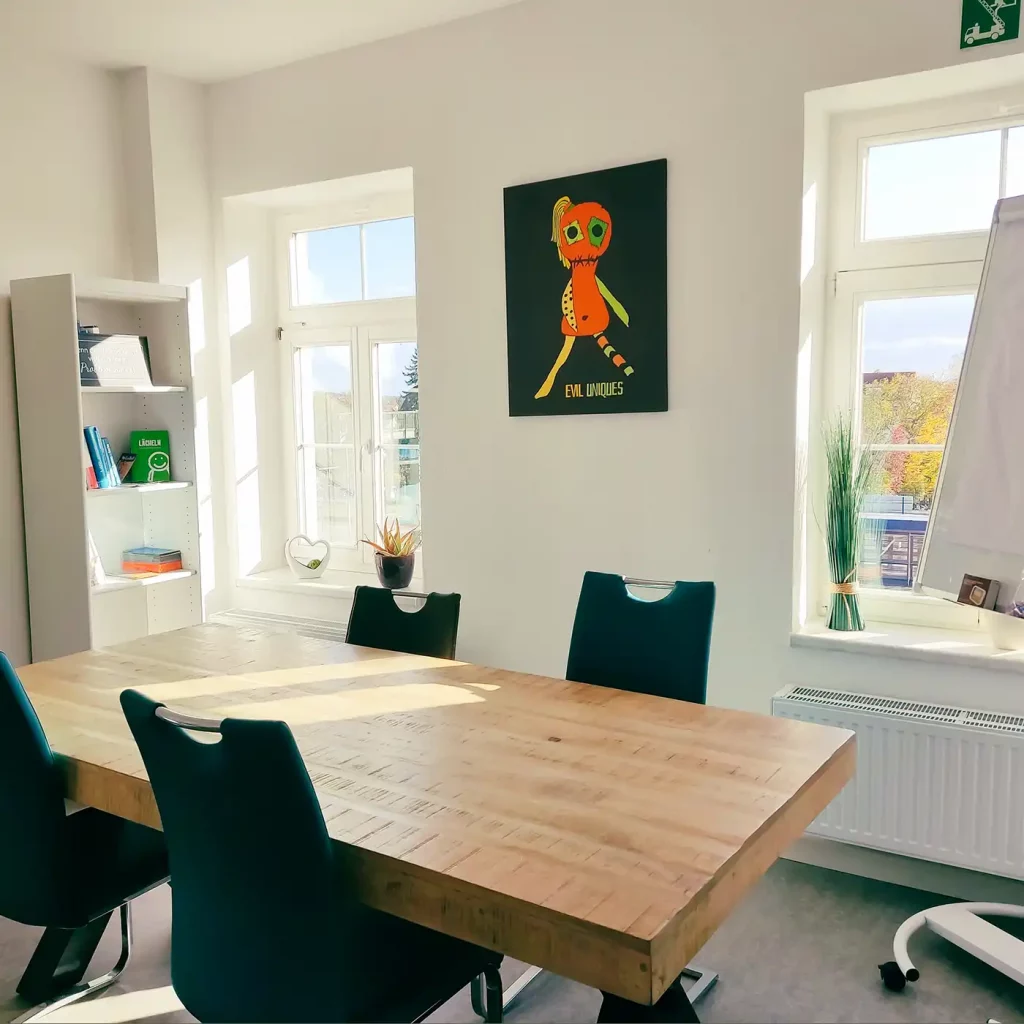 Ein Therapiezimmer mit einem Tisch, an dem 6 Stühle stehen.